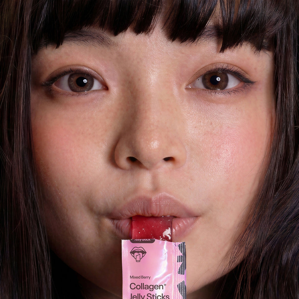 Close-up of a woman holding a RIN Collagen Jelly Stick packet to her lips.