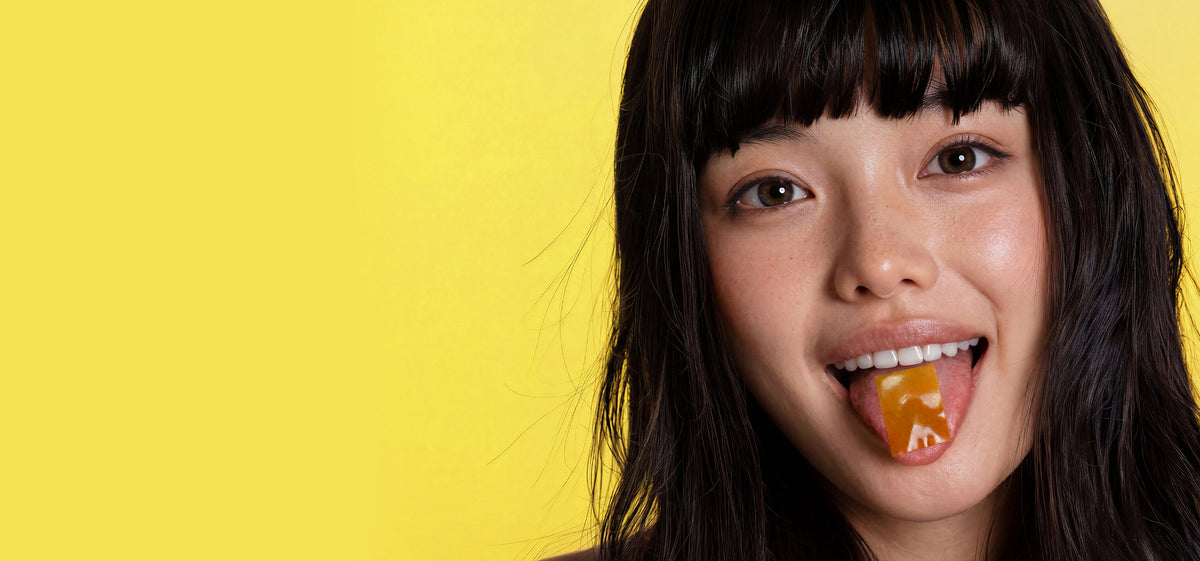 A close-up of a woman with a RIN Glow Strip on her tongue