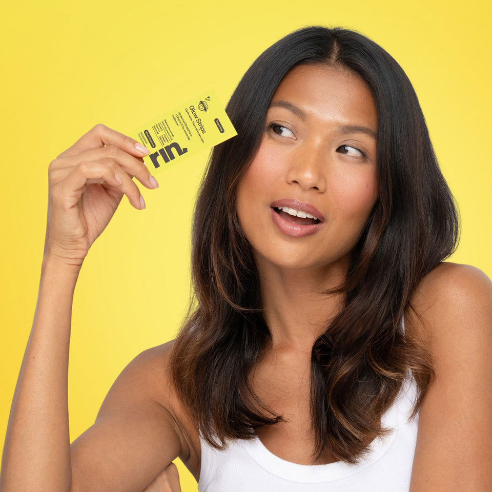 Woman holding a yellow RIN Glow Strips sachet against a bright yellow background.