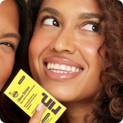A smiling woman holding a RIN Glow tongue strip sachet.